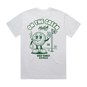 A white short-sleeve t-shirt shown from the back, featuring a green graphic print of a cartoon golf ball character on a golf course with the text 'ON THE GREEN', 'Haitch Golf', 'GOLD COAST AUSTRALIA', and 'SINCE 2024'.