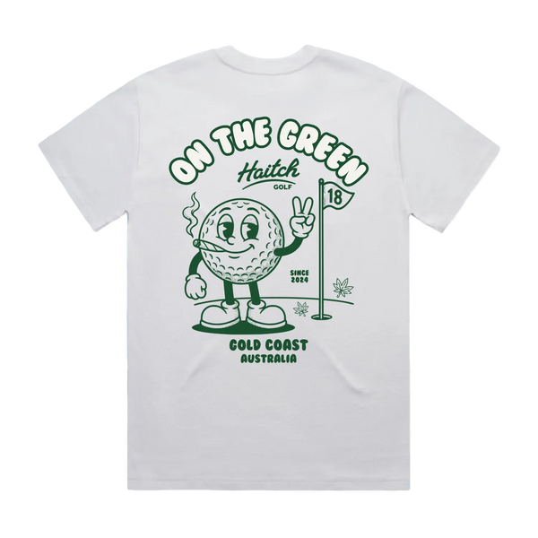 A white short-sleeve t-shirt shown from the back, featuring a green graphic print of a cartoon golf ball character on a golf course with the text 'ON THE GREEN', 'Haitch Golf', 'GOLD COAST AUSTRALIA', and 'SINCE 2024'.
