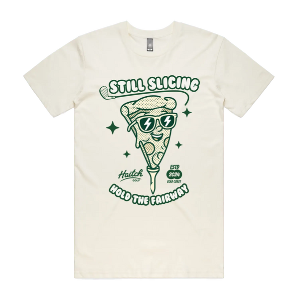 An off-white short-sleeve t-shirt with a green graphic of a slice of pizza wearing sunglasses, with the text 'STILL SLICING' and 'HOLD THE FAIRWAY'.