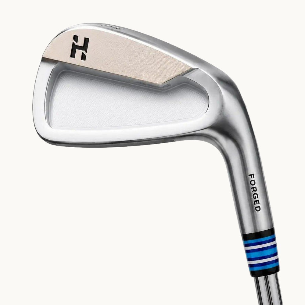 A close-up studio shot of a Haitch Golf Marksman CB forged iron golf club head and part of the shaft on a light off-white background, with product text below.
