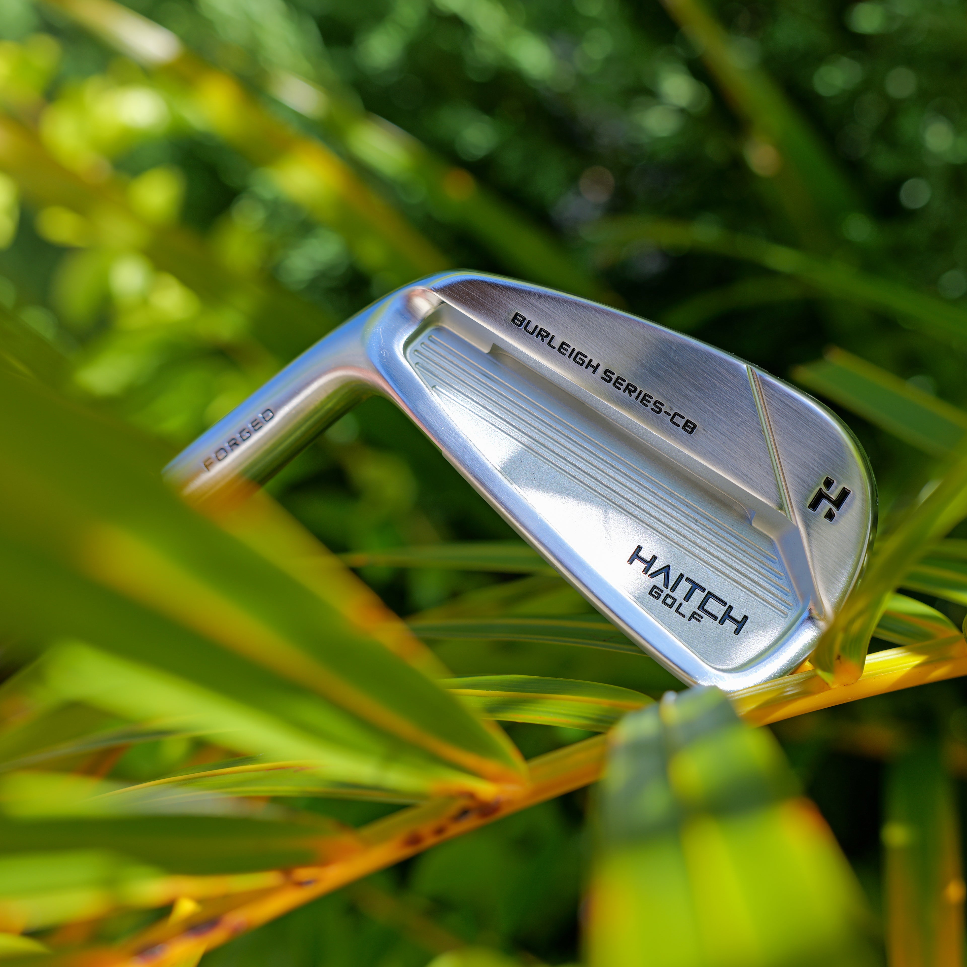 Golf club head with 'Hatch Golf' branding in a grassy setting